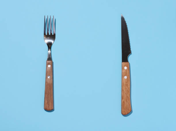 istock Fork and knife with wooden handle on blue background, top view 1465529715
