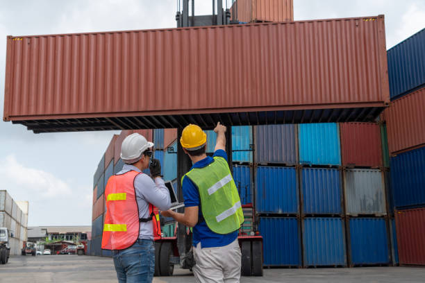 istock Industrial worker works with co-worker at overseas shipping container yard . Logistics supply chain management and international goods export concept . 1465530253