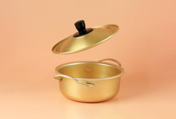 Brass Pot Korean Ramyeon Pan Soup with Flying Lid. Isolated on Peach Background, Copy Space