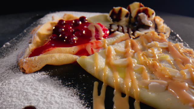 Sweet pancakes topped with cherry syrup, cheese, banana and chocolate