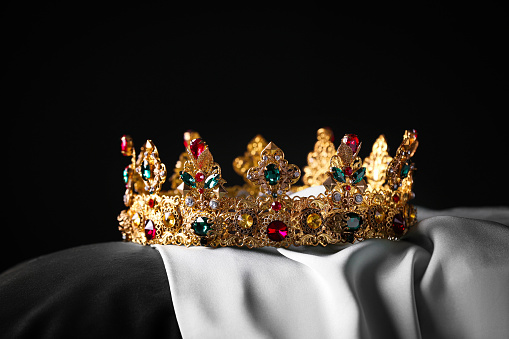 Decorative gold crown on a red plinth. Red background with copy space