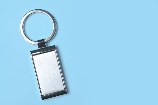 Metallic keychain on light blue background, top view. Space for text