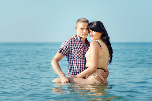 a guy and a girl walk along the seashore, swim in the water