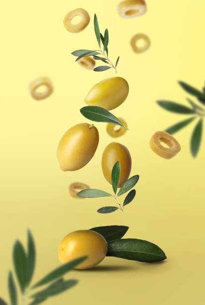 istock Fresh olives and leaves falling on pale yellow background 1465534635