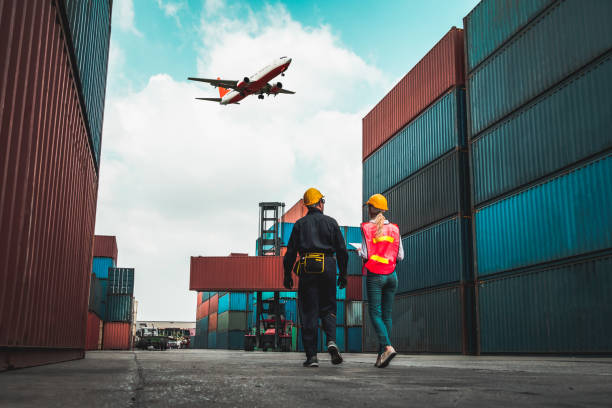 istock Industrial worker works with co-worker at overseas shipping container port . Logistics supply chain management and international goods export concept . 1465536927