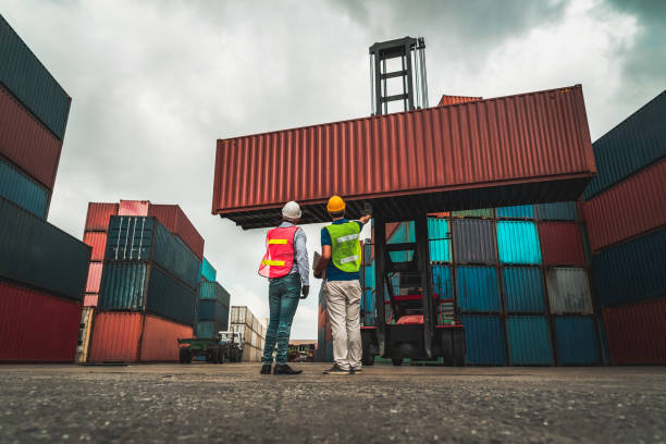istock Industrial worker works with co-worker at overseas shipping container yard . Logistics supply chain management and international goods export concept . 1465537215