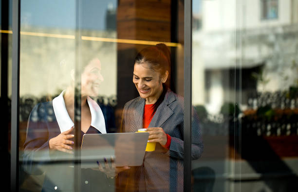istock Two happy businesswomen discussing using laptop and drinking coffee at office 1465539538