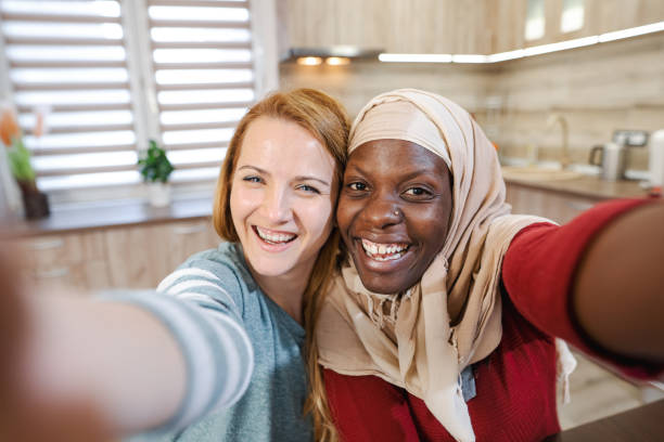 istock Two multiracial female friends taking selfies together 1465540916
