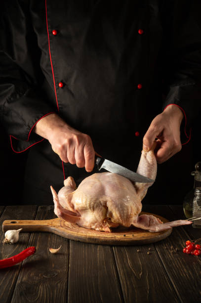 istock Professional chef cuts raw chicken with a knife in the kitchen. Cooking chicken for lunch. Grande cuisine. 1465542431