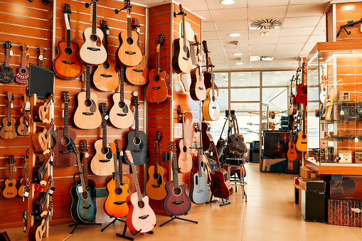 A huge assortment of different guitars hanging on the walls in a musical instrument store. Hobbies and recreation.