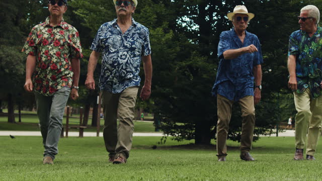 Cool-Looking Senior Men in Sunglasses and Colorful Hawaiian Shirts Walking Confidently Towards the Camera in Slow Motion. They Fist-bump. Serious Elderly Males Fighting Stereotypes and Ageism