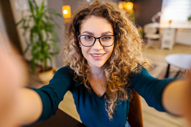 istock Beautiful young woman holding camera and taking selfies 1465543466