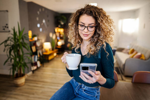 istock Young woman relaxing at home, drinking coffee and using mobile phone 1465543469