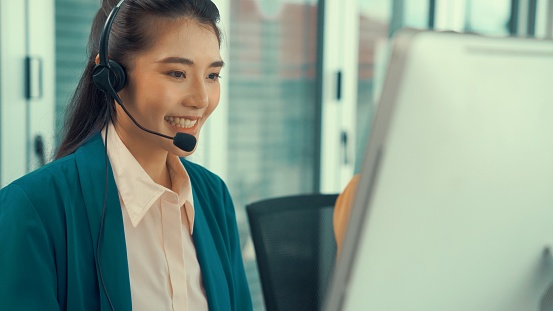 Businesswoman wearing headset working actively in office . Call center, telemarketing, customer support agent provide service on telephone video conference call.