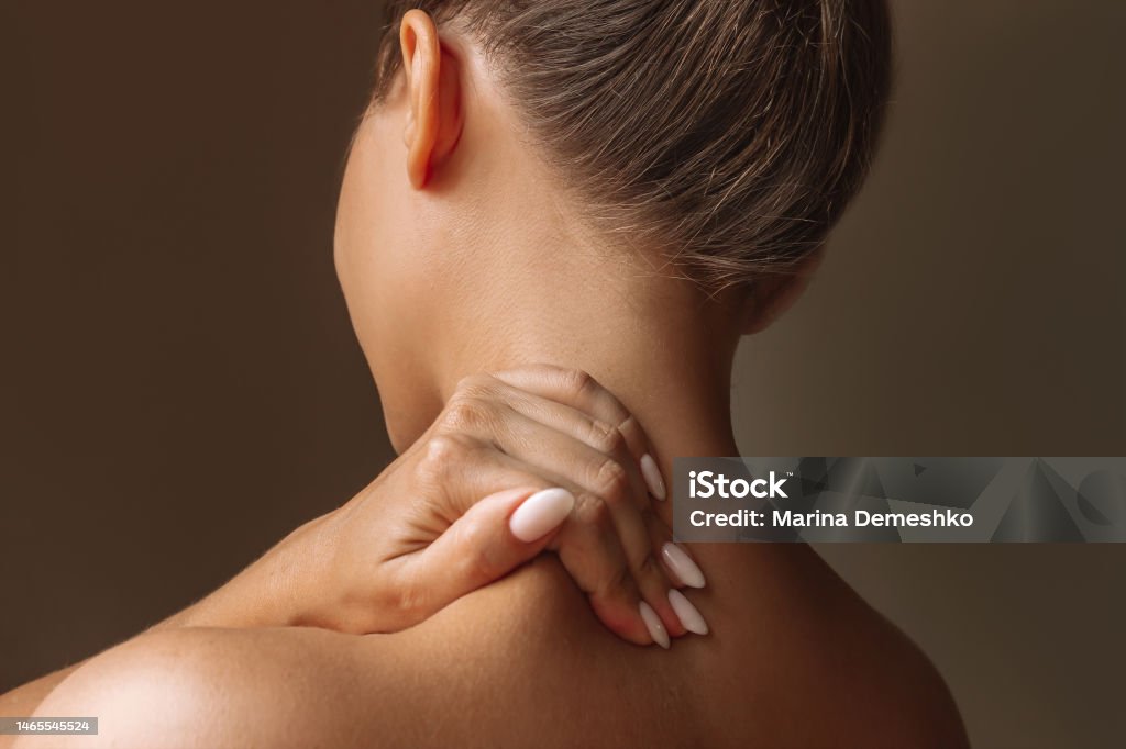 Cropped Shot Of A Young Woman Standing With Her Back Holds Her Neck  Massaging A Trapezius Muscle With Her Hand Stock Photo - Download Image Now  - iStock