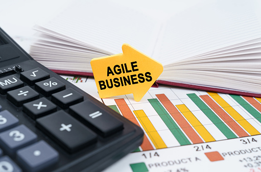 Business concept. On the business charts there is a notepad, a pen and an arrow sticker with the inscription - Agile Business