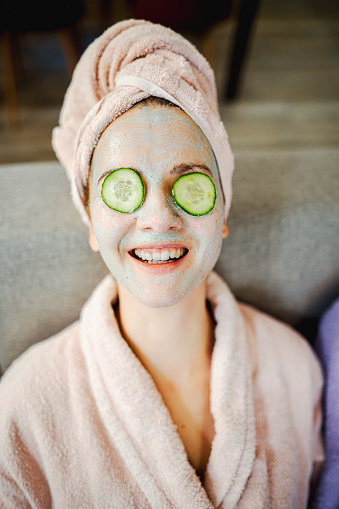 Woman relaxing while lying down with face mask and cucumber circles  on eyes