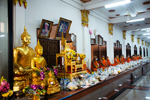 Monks sitting between thai people join tradition make merit offer food to the monk and ritual respect praying blessing wish holy at Wat Lat Pla Duk Temple on February 5, 2023 in Nonthaburi, Thailand