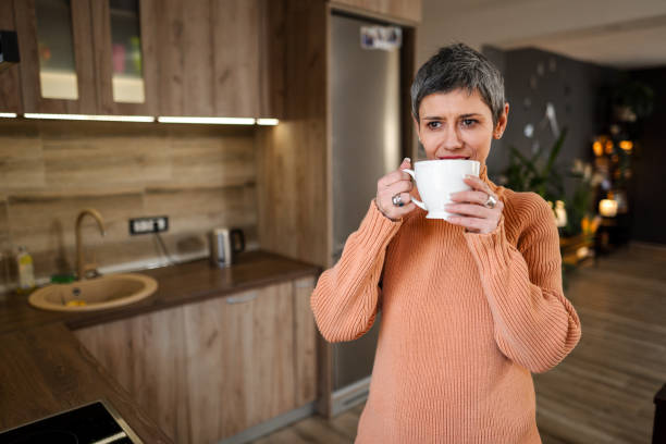 istock Mature woman drinking her morning coffee while standing in front of kitchen window 1465556120