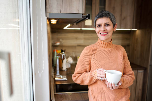 istock Mature woman drinking her morning coffee while standing in front of kitchen window 1465556181