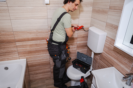 Plumber in bathroom fixing a problem with water pipes