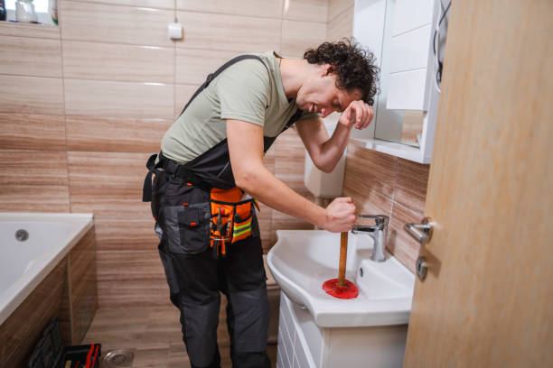 istock Tired plumber fixing clogged bathroom sink with plunger 1465558956