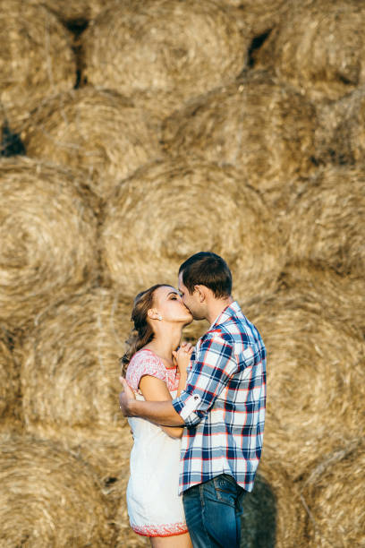 a guy with a girl on a summer walk in the field near round haystacks