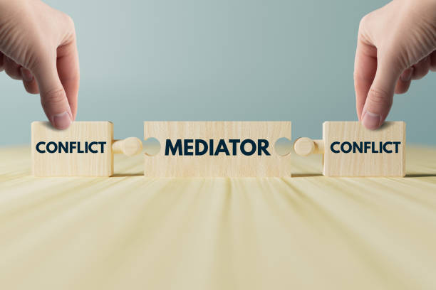 istock Wooden blocks, puzzles with the word conflict and a mediator that connects them. 1465562483