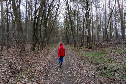 Girl in red jacket walking through the woods