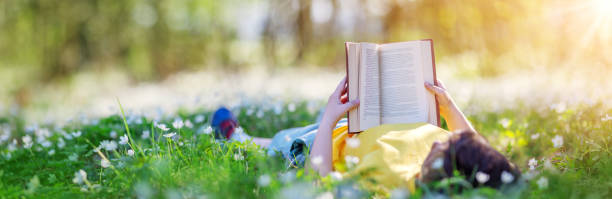 istock Small child lying down on the field in the spring park and reading a book 1465566855