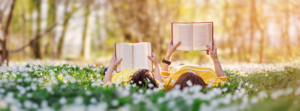 madre y su hijo acostados en el hermoso campo de primavera en el soleado parque. - lectura de verano fotografías e imágenes de stock