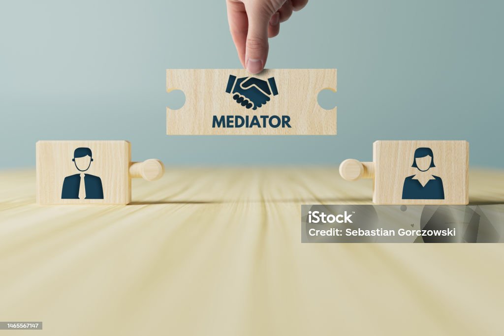 The hand holds wooden wooden blocks with icons of a woman and a man and shaking hands in the act of consent. The concept of divorce, agreement, mediation, the role of the mediator. Mediation Stock Photo