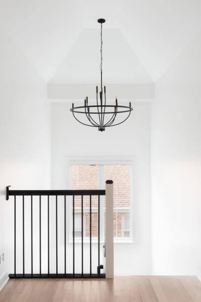 A staircase with a chandelier hanging from a tall ceiling.