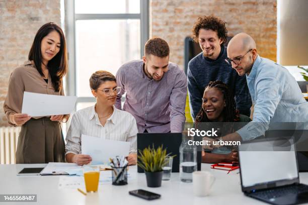 Colleagues Watching Something On Laptop While At The Office Stock Photo - Download Image Now