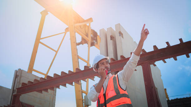 istock Professional Asian male civil engineer or architect wear safety helmet. While working using walkie-talkie talking to someone checking list project on construction site. 1465568506