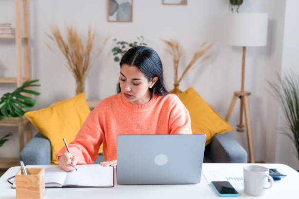 istock woman writing in notepad working from home 1465569698