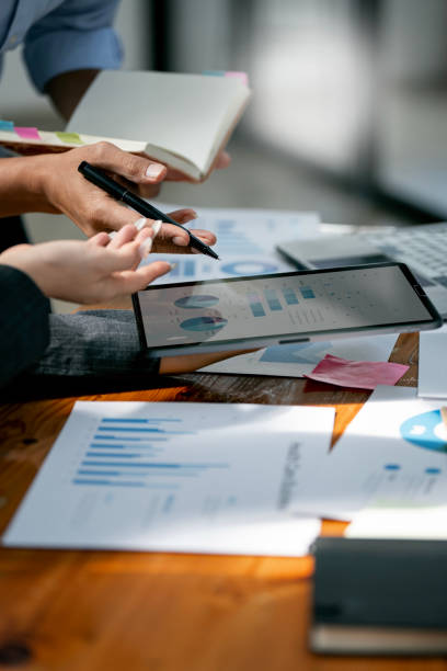 istock Two confident business people point to graphs and charts on tablet to analyze data, balance sheet, account and net profit 1465570048