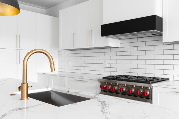 istock A gold faucet detail in a modern white kitchen. 1465570733