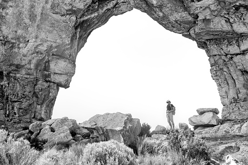 Sanddrif, South Africa - Sep 7, 2022:A person is visible inside the main Wolfberg Arch near Sanddrif in the Western Cape Cederberg. Monochrome