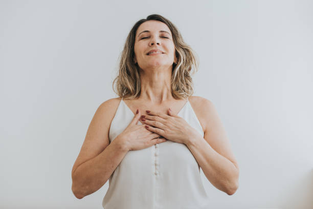 retrato de una mujer madura respirando con las manos en el pecho - breathe fotografías e imágenes de stock