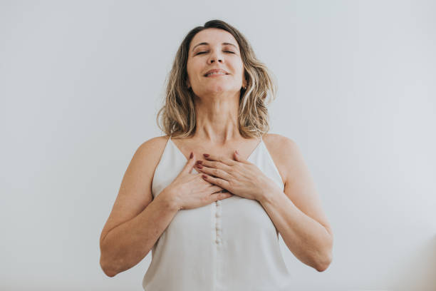 portrait d’une femme mûre respirant avec ses mains sur sa poitrine - exercice de respiration photos et images de collection