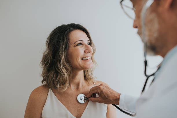 Doctor listening to patient's heart with stethoscope stock photo