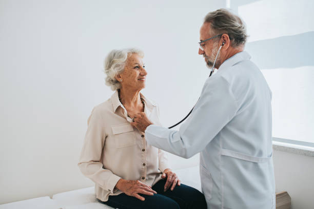 doctor listening to senior woman patient heartbeat - outpatient imagens e fotografias de stock