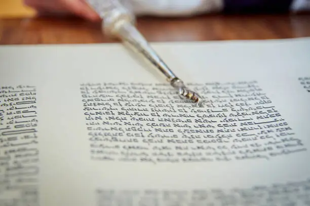 Close Up of Yad Pointing at Hebrew Letters in Torah Scroll
