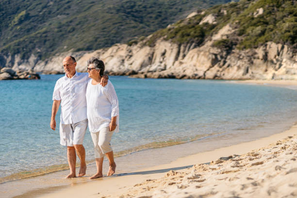 istock Senior Couple Walking On The Sunny Beach 1465576183