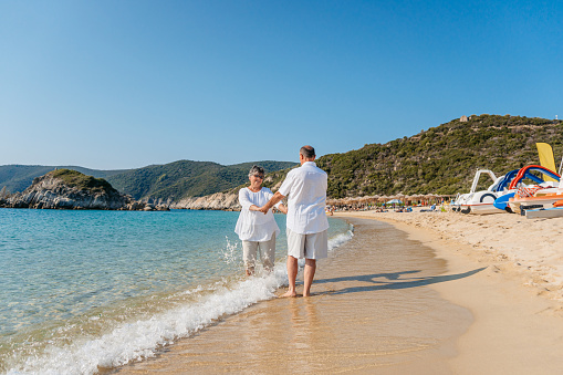 Happy senior couple dancing on the sunny beach in Sithonia, Greece.