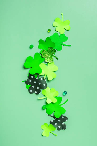 istock St. Patrick's Day minimalistic flat lay composition. Paper clover leaves on colored background with copy space 1465576403