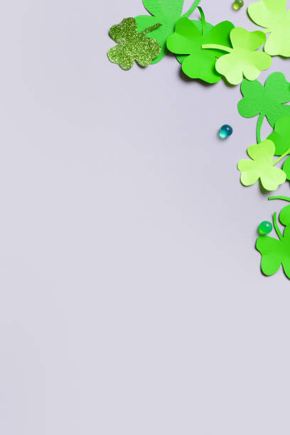 istock St. Patrick's Day minimalistic vertical background. Paper clover leaves on grey background with copy space 1465576430