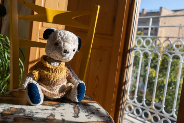 istock Teddy bear on yellow chair next to window on sunny day 1465578366
