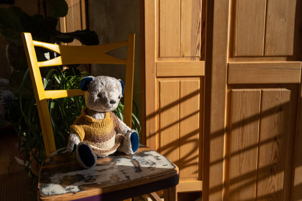 istock Teddy bear on yellow chair next to window on sunny day 1465578388